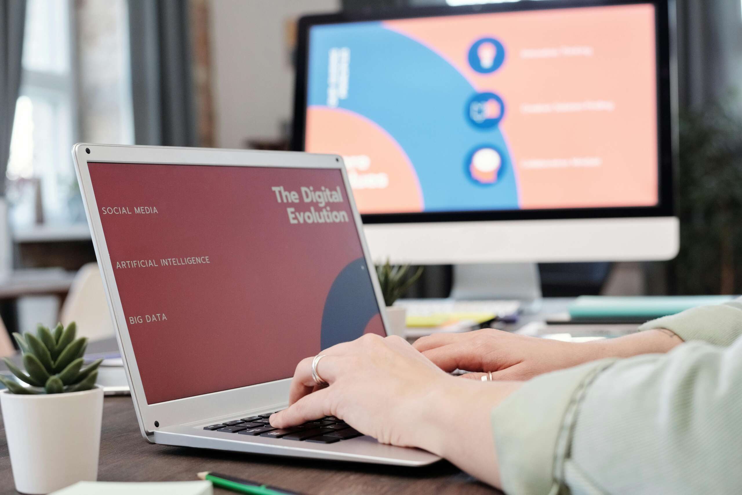 A close-up picture of hands working on a laptop with the screen reading “The Digital Evolution”.